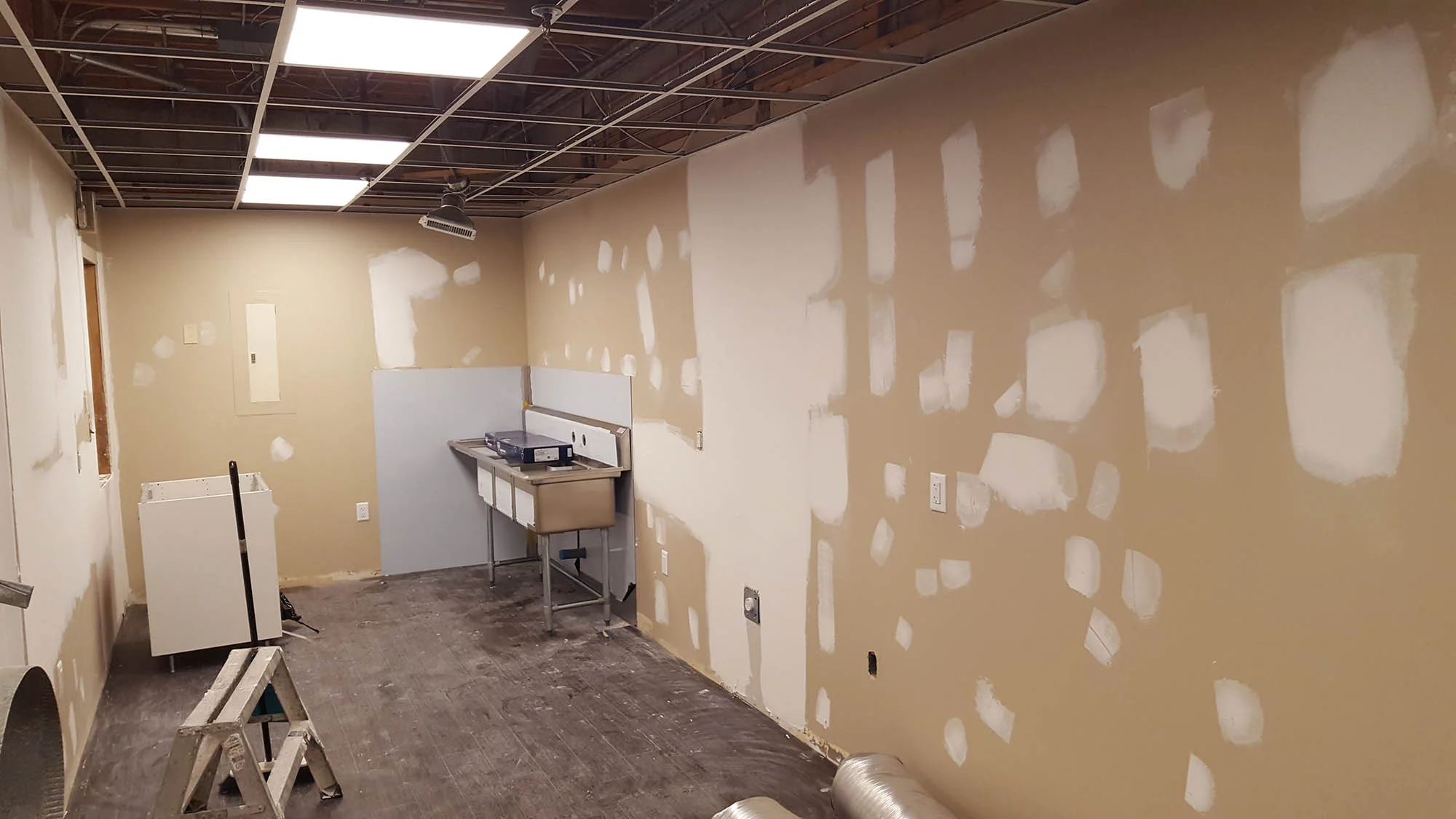 Community kitchen renovation in Calgary, mid-build — the aging ceiling grid opened up and the room stripped back to a shell, August 2017