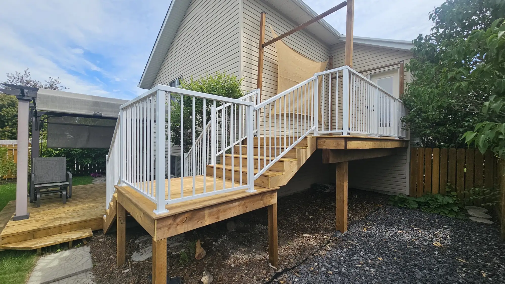 A two-level pressure-treated deck with white aluminium railings and a stair run, built on an Airdrie home by Suite Home Renovations