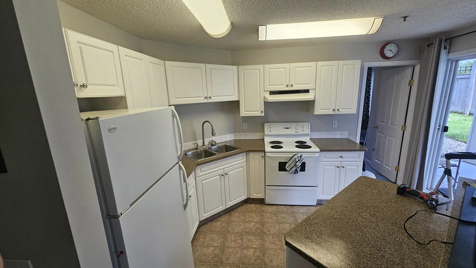 Dover kitchen before renovation — white raised-panel cabinets, laminate counters and a fluorescent box light, Calgary