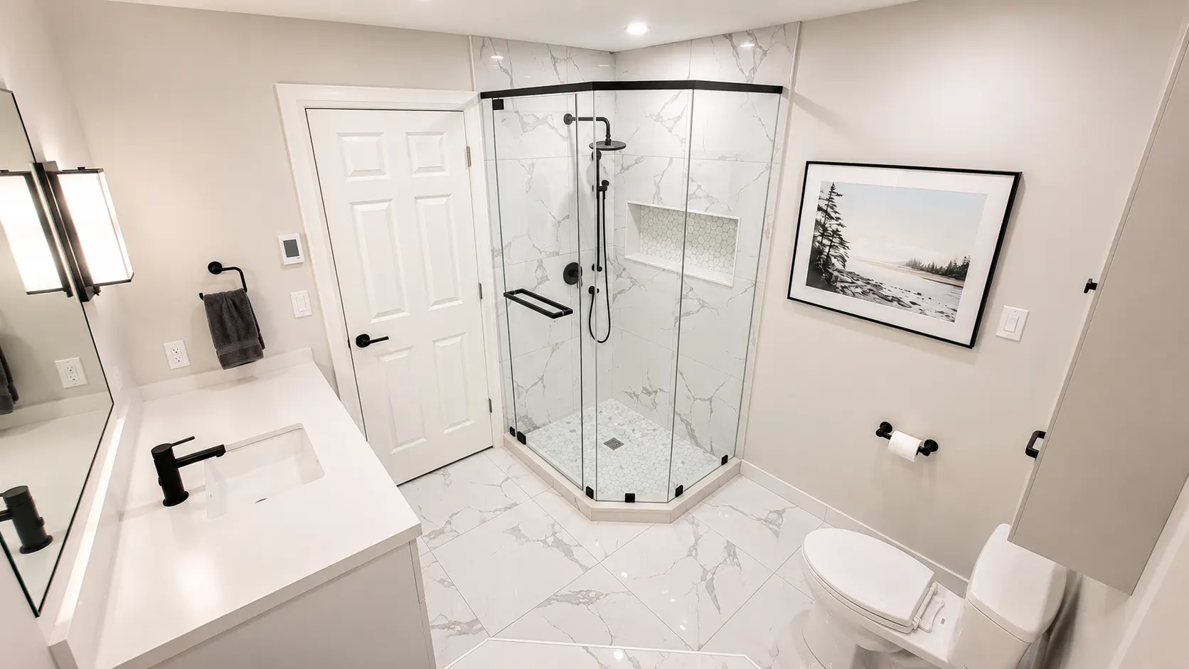 Ensuite shower in a Spruce Cliff renovation, Calgary — a neo-angle glass enclosure in marble-look tile with a lit niche