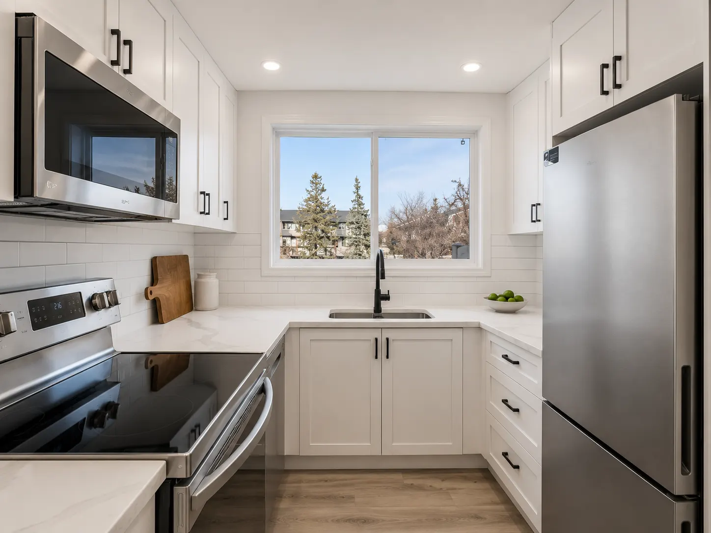 Galley kitchen renovation in Braeside, Calgary — white shaker cabinets, black hardware and quartz counters