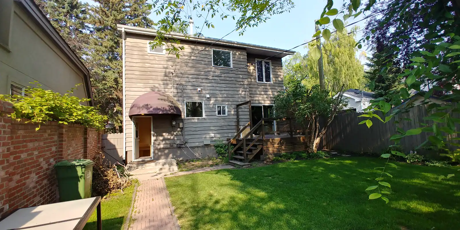 Mount Royal backyard before renovation — weathered siding, a dome awning and a small aging deck