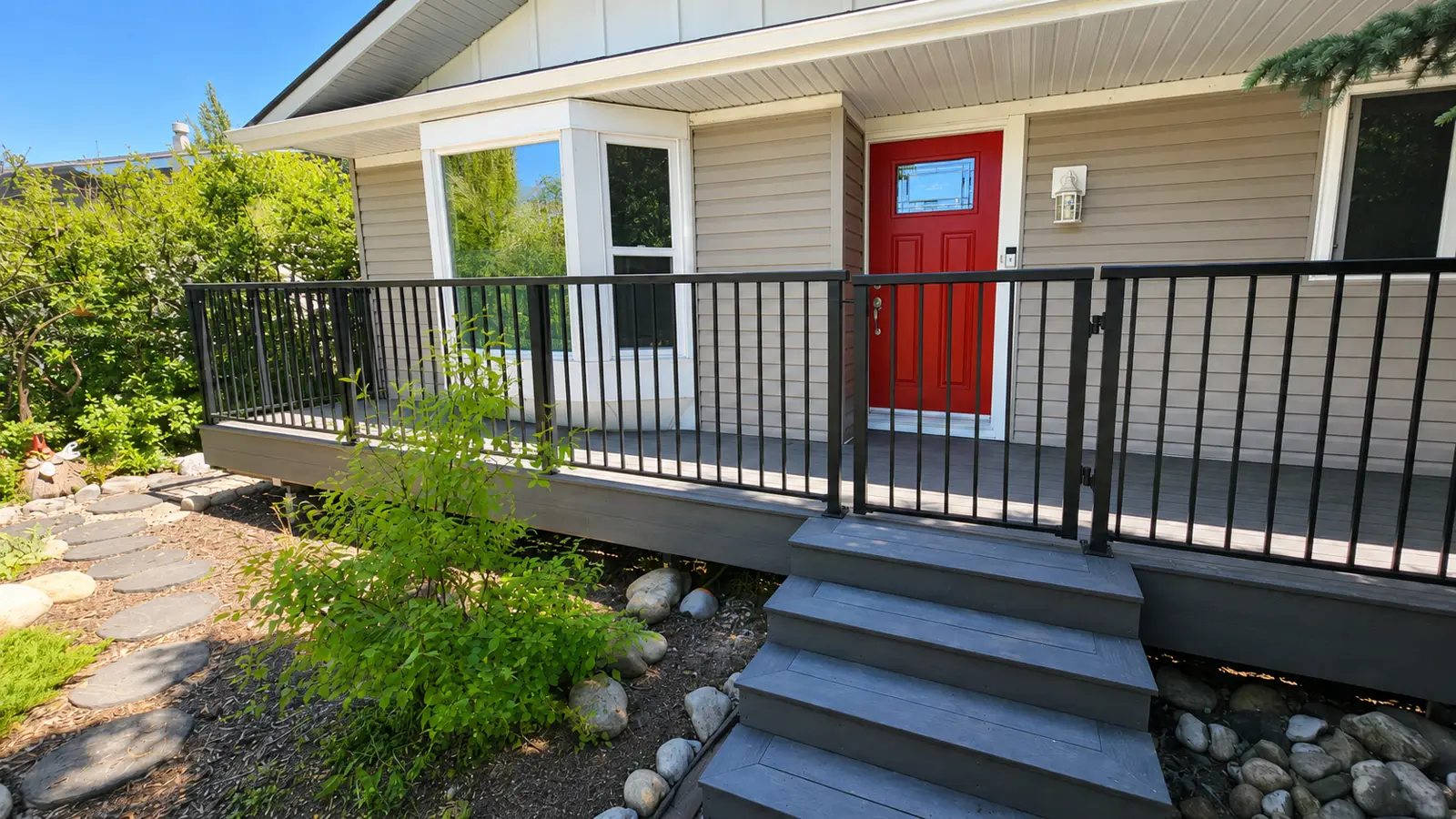 Grey composite front porch with black railings and a red door from an Okotoks deck and yard renovation, Calgary
