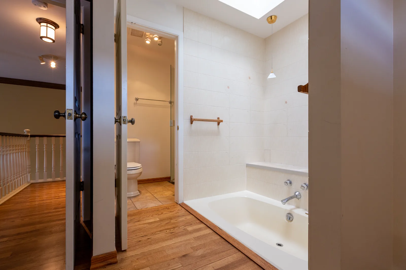 Rideau ensuite renovation in Calgary, before — a white drop-in soaker tub in a white-tiled alcove beneath a skylight